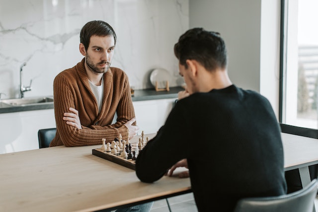 Dwóch mężczyzn grających w szachy przy stole kuchennym