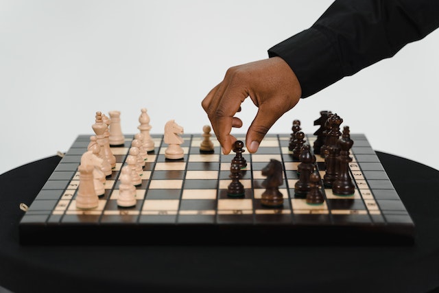 Mężczyzna przesuwający pionek na szachownicy