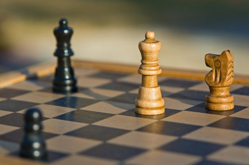 Król, hetman, wieża i pionek ustawione na szachownicy w trakcie gry